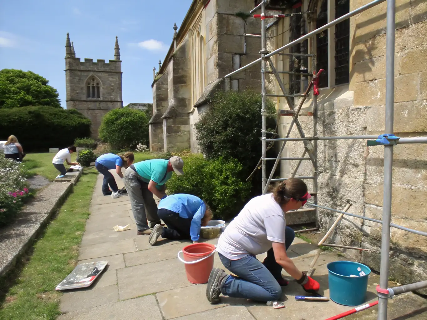 A group of volunteers working together to restore a historic stone wall in Coulaures, showcasing community involvement in heritage preservation.